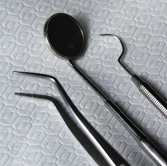 Set of shiny dental and surgical instruments arranged on a hexagon-patterned cloth